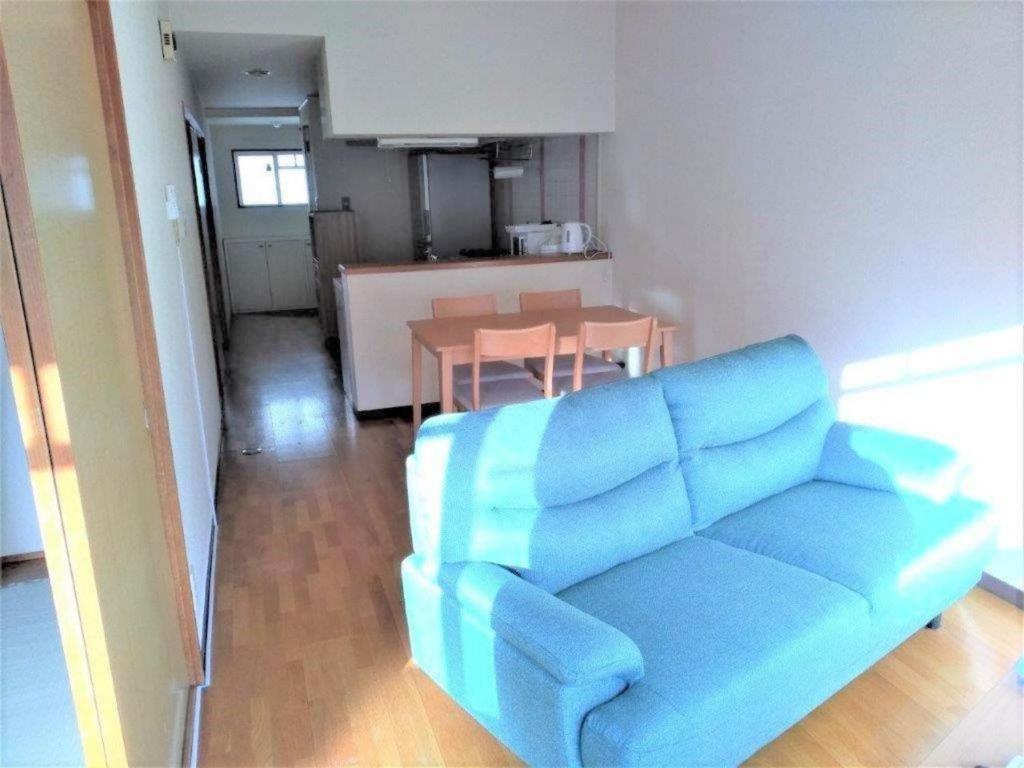 uma sala de estar com um sofá azul e uma mesa em Maison Ota Building A Building B - Vacation STAY 12386 em Takamatsu