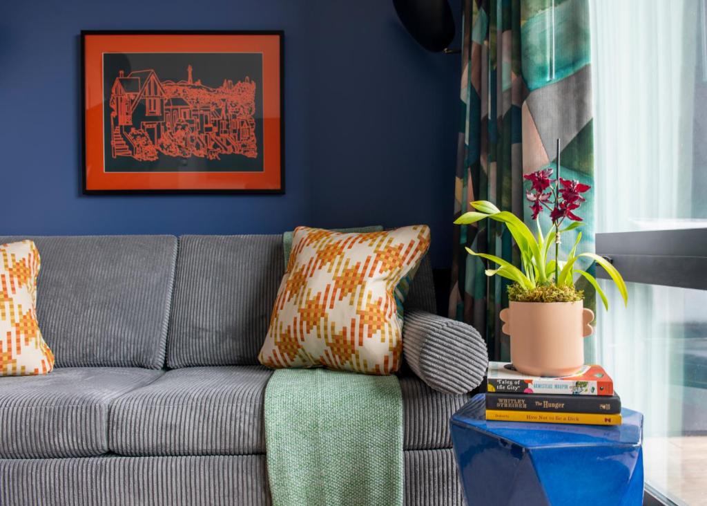 uma sala de estar com um sofá cinzento e uma planta em The Hotel Castro San Francisco em São Francisco