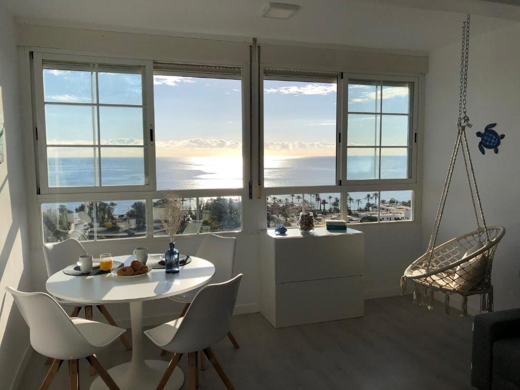 een eetkamer met een tafel en stoelen en grote ramen bij Studio Infinity Sea in Aguadulce