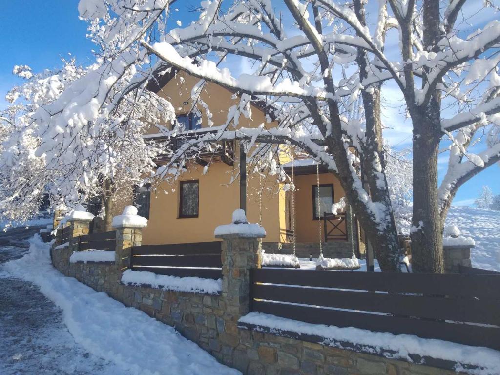 a house covered in snow in front of a fence at Садиба Лісова in Podgorodtsy