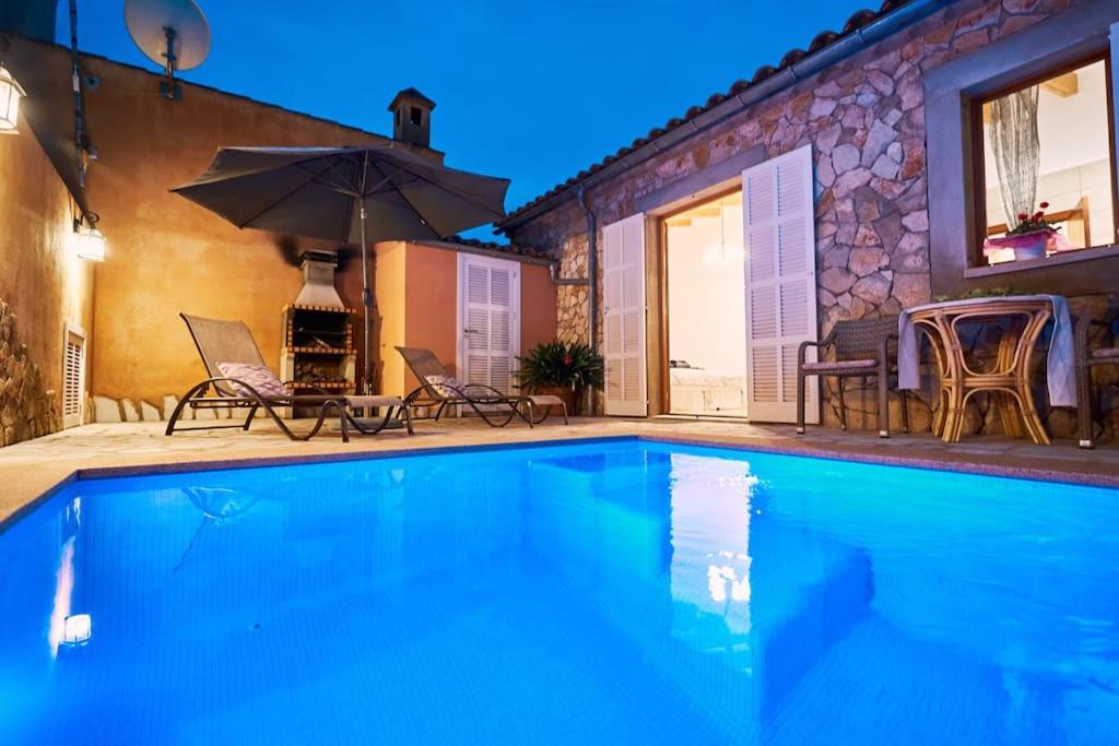 uma piscina com duas cadeiras e um guarda-sol em Can Diego em Vilafranca de Bonany