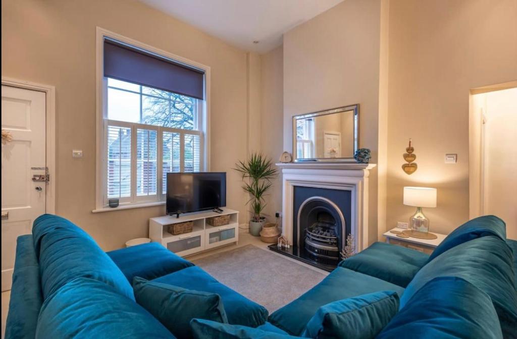 a living room with a blue couch and a fireplace at Choristers Mews: Luxury cottage a stones throw from the Cathedral! in Lincolnshire