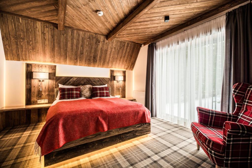 a bedroom with a red bed and two chairs at Gościniec Kuźnice in Zakopane