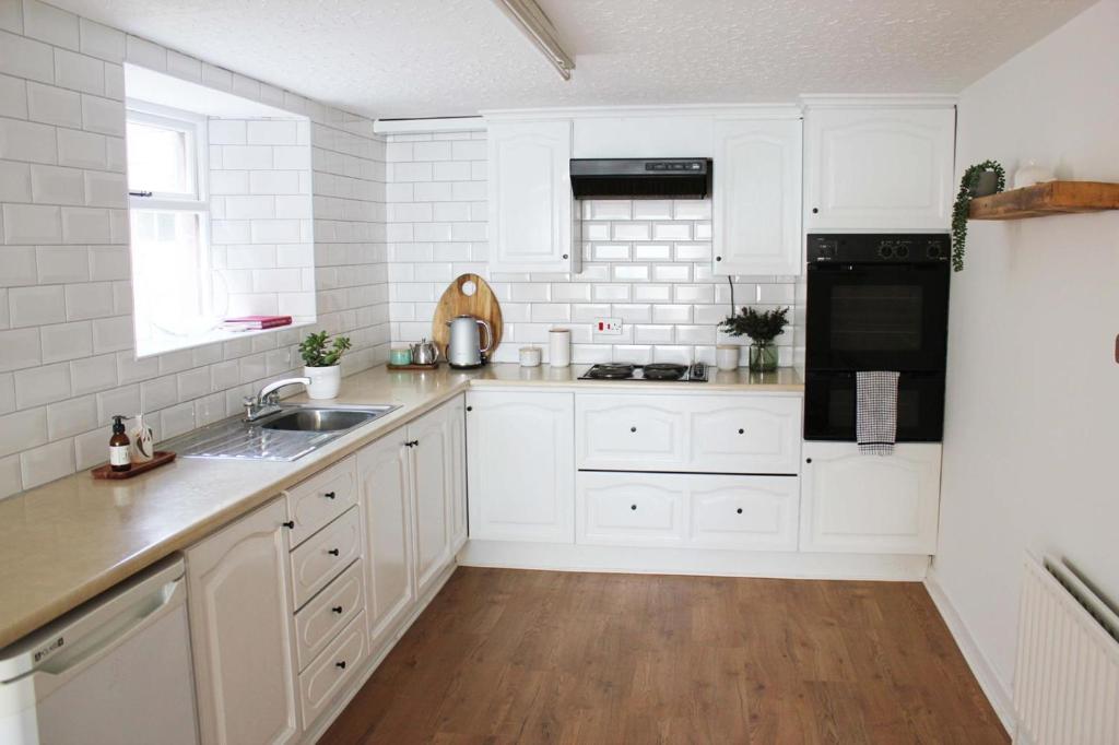 a white kitchen with white cabinets and a sink at 'A room with seaview' on Carlingford Lough in Warrenpoint