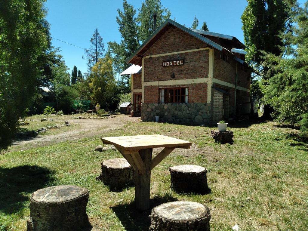 een picknicktafel en wat boomstammen voor een gebouw bij Hostel Casona Alameda in El Bolsón