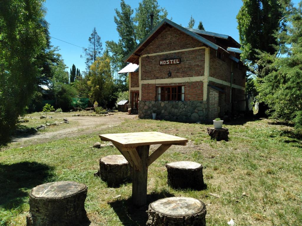 una mesa de picnic y algunos troncos delante de un edificio en Hostel Casona Alameda en El Bolsón
