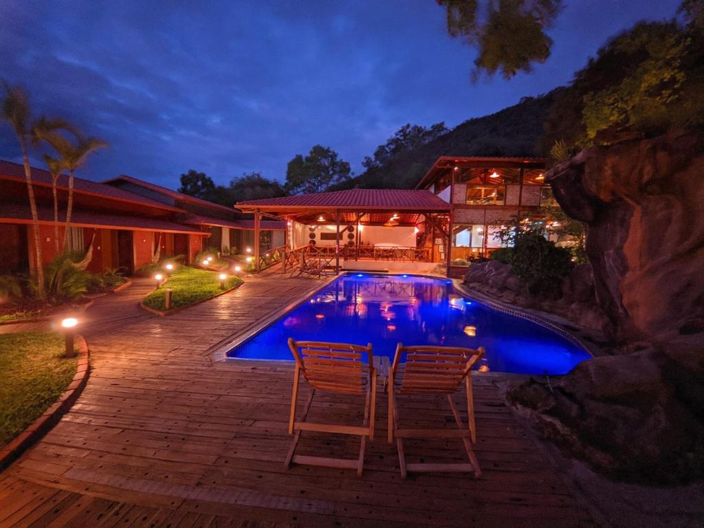 una casa con una piscina con 2 sillas junto a ella en Pousada Meraki, en Serra do Cipo