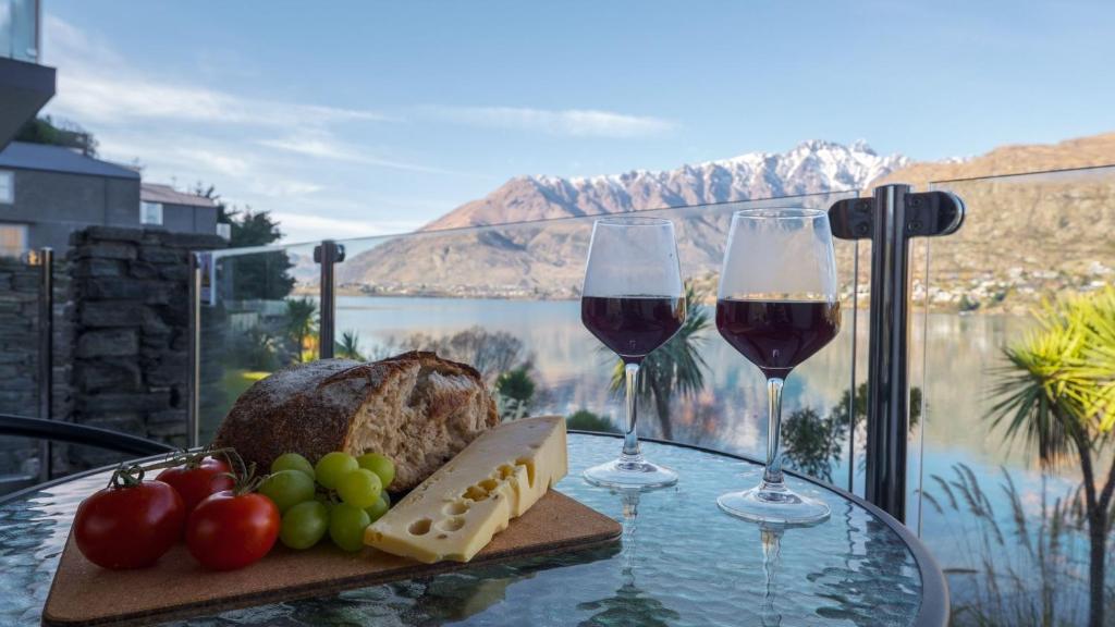 een tafel met twee glazen wijn en een bord eten bij Alpine Lakeside Studio in Queenstown