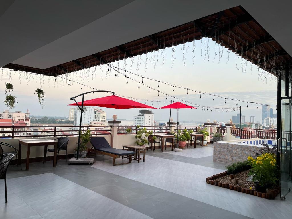a patio with tables and umbrellas on a roof at Queenwood Hotel in Phnom Penh