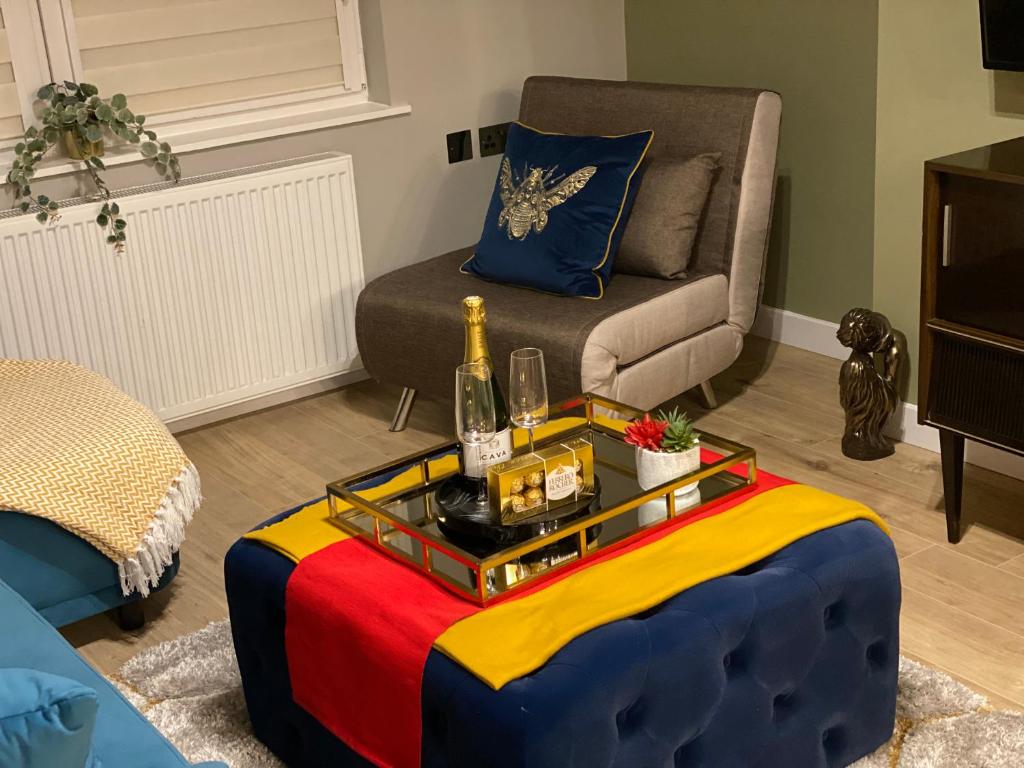 ein Wohnzimmer mit einem bunten Tisch und einer Flasche Champagner in der Unterkunft Lovely 3 bed with jacuzzi, close to airport, driveway, wifi in Edinburgh