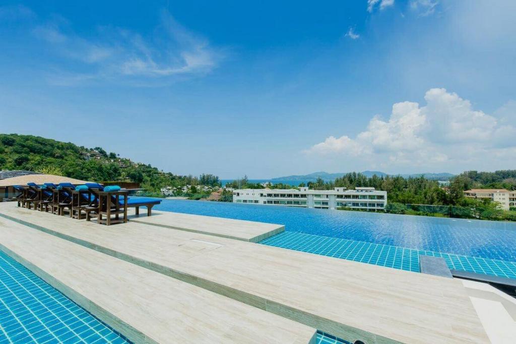 a swimming pool with tables and chairs on a building at Aristo 1 Phuket in Phuket Town