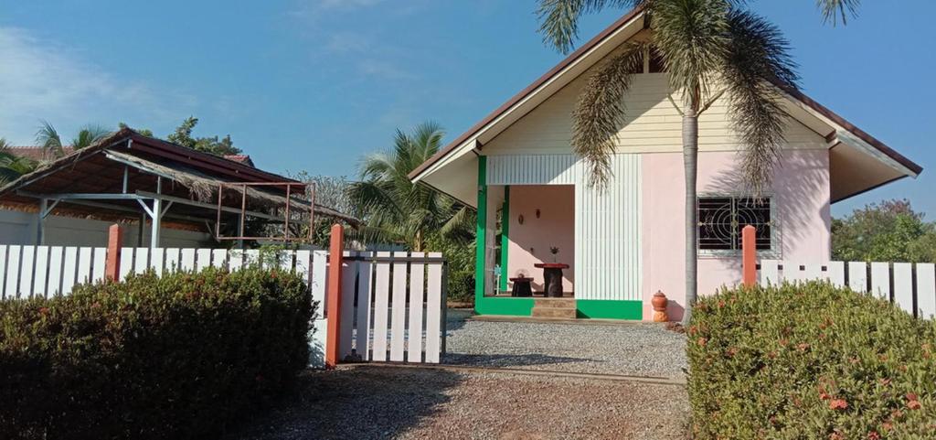 una casa con una recinzione bianca davanti di Bungalow 36 m2 sur terrain 400m2 avec Piscine privée a 12km de BAN DUNG a Ban Dung