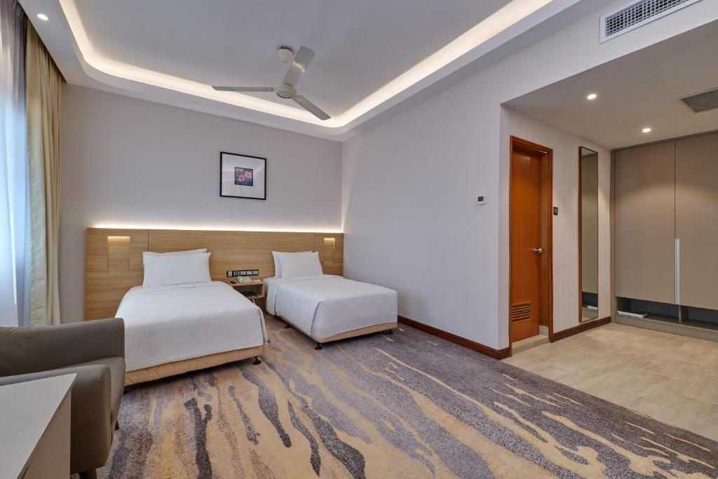 A twin room with two single beds, a lounge chair, wardrobe and entry area.