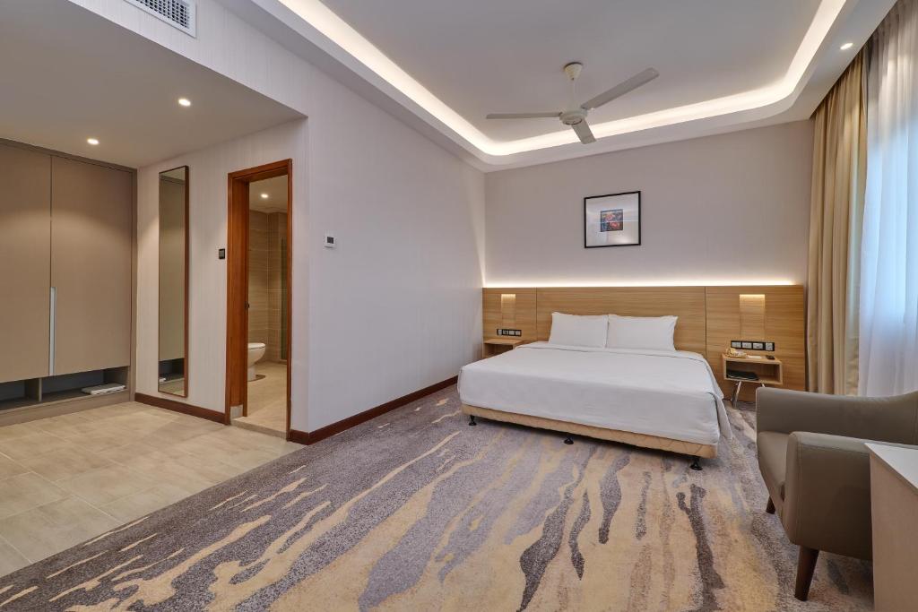 A spacious-looking room with one bed, a desk, wardrobe storage and a sitting chair.
