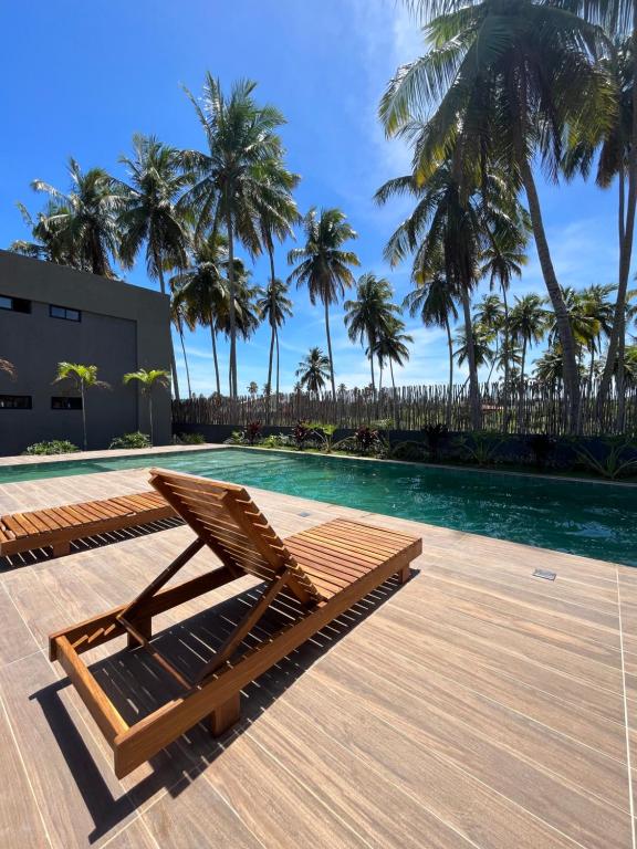 a lounge chair next to a swimming pool with palm trees at Patacho Beach - Milagres - Rota Ecológica in Pôrto de Pedras