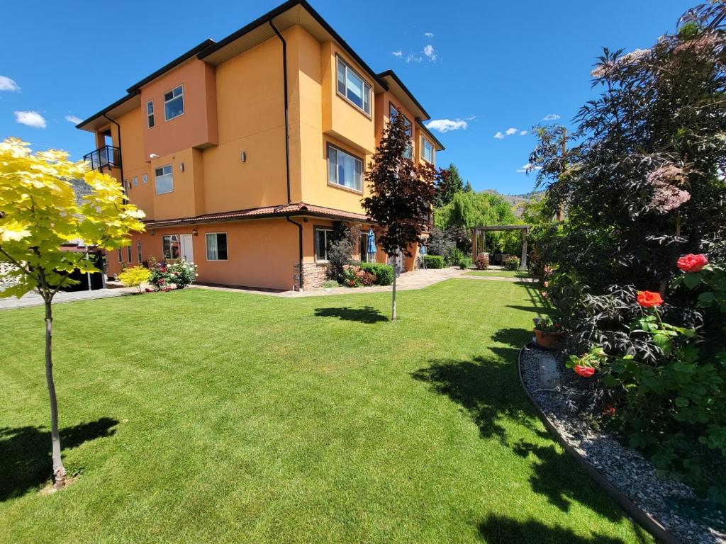 a house with a yard with grass and flowers at Sahara Suites in Osoyoos