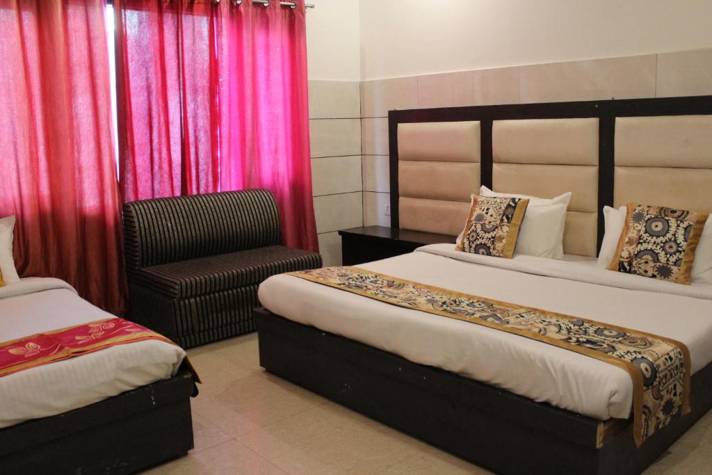 a hotel room with two beds and a chair at Trimrooms JMC Katra Railway Road in Katra