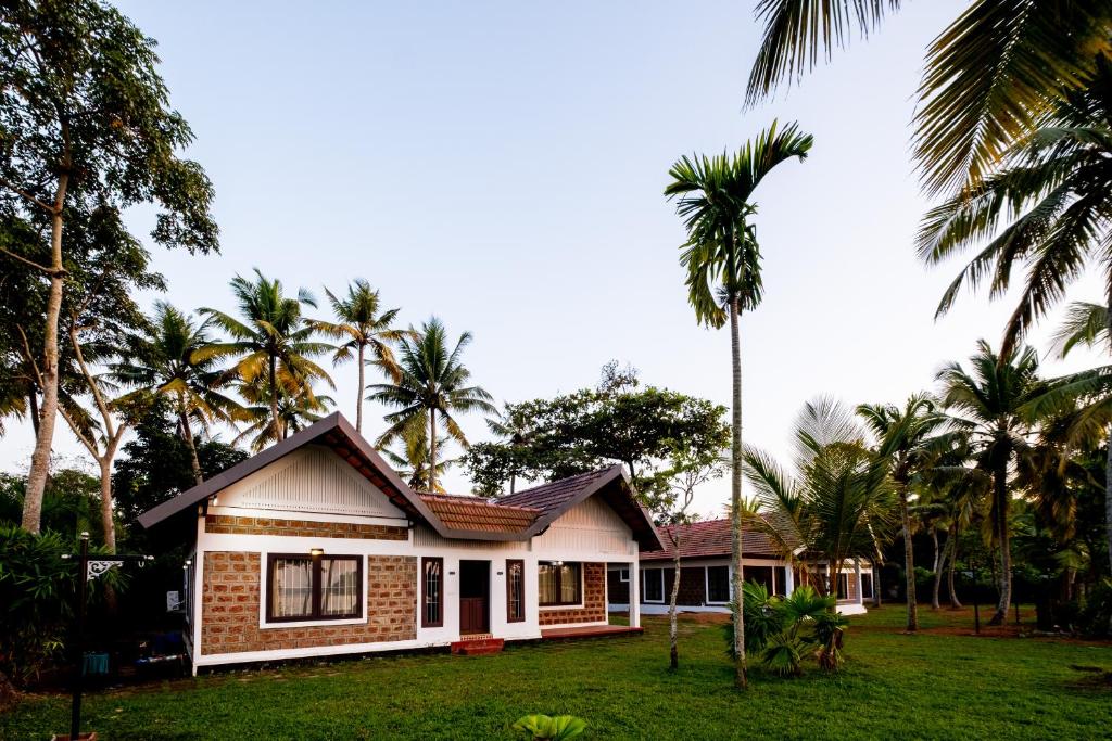 una casa con palmeras delante en Cynefin, Pet-friendly 2br by the backwaters by Roamhome, en Murinjupuzha