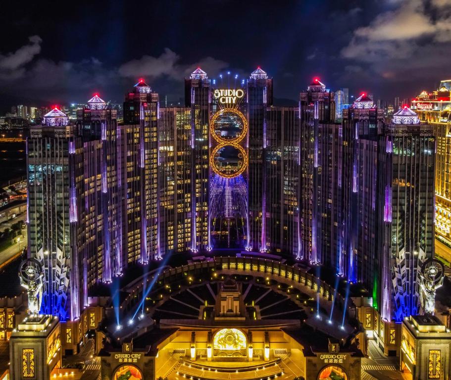 
a large clock tower towering over a city at night at Studio City Hotel in Macau
