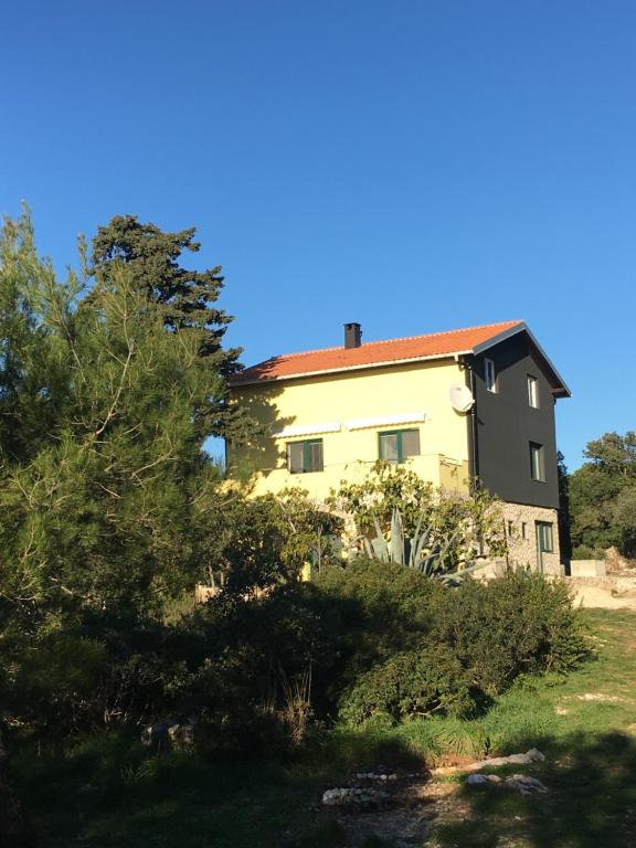 ein gelbes Haus mit rotem Dach in der Unterkunft APARTMENT ŽUŽI Otok Silba Hrvatska in Silba