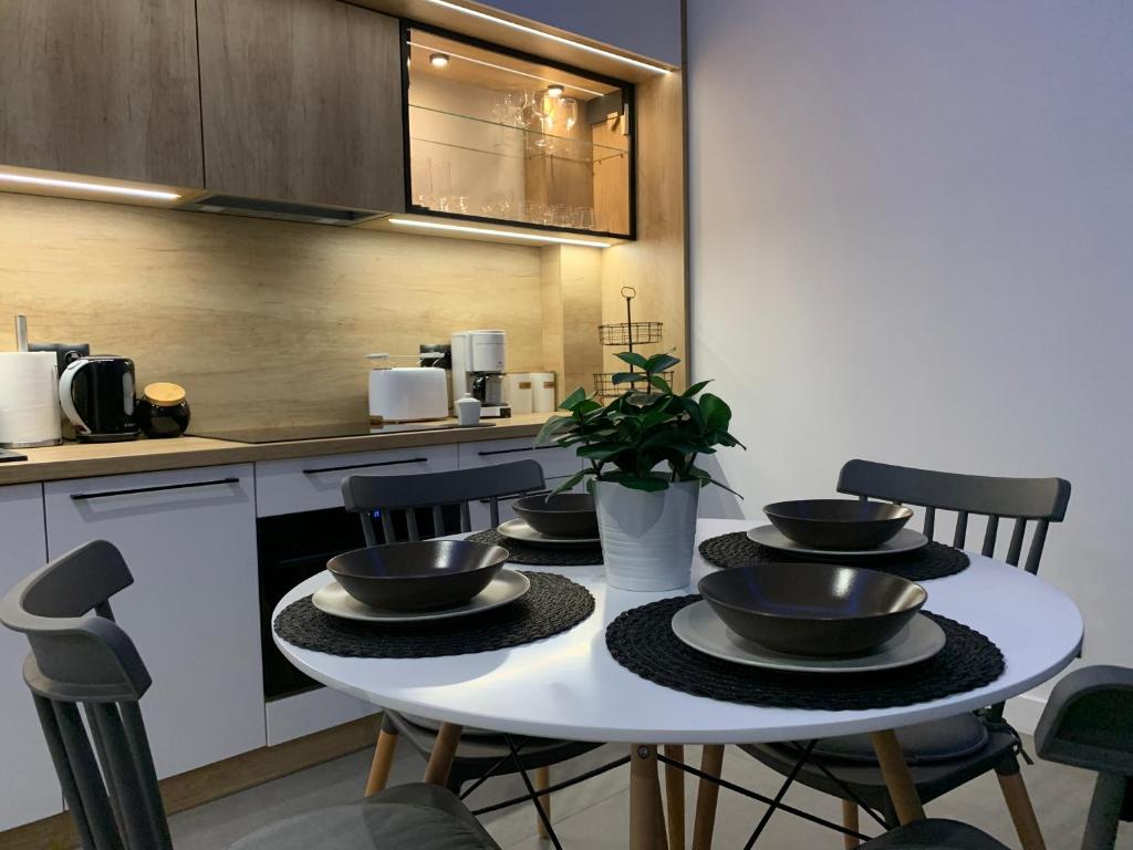 a kitchen with a white table with bowls on it at Apartamenty Misdroy Parking Gratis 250 m od plaży in Międzyzdroje