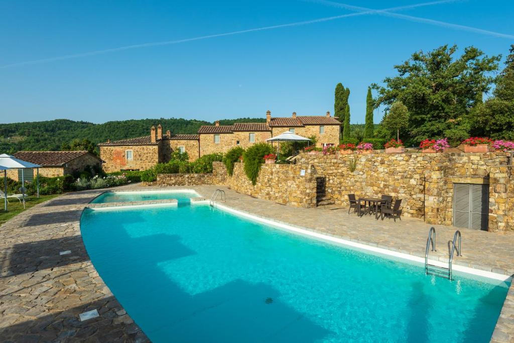einem großen Pool vor einem Steingebäude in der Unterkunft Piccolo Borgo Gagnoni in Sinalunga
