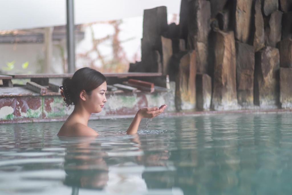 una joven nadando en una piscina de agua en Kusatsu-onsen Hotel Resort, en Kusatsu