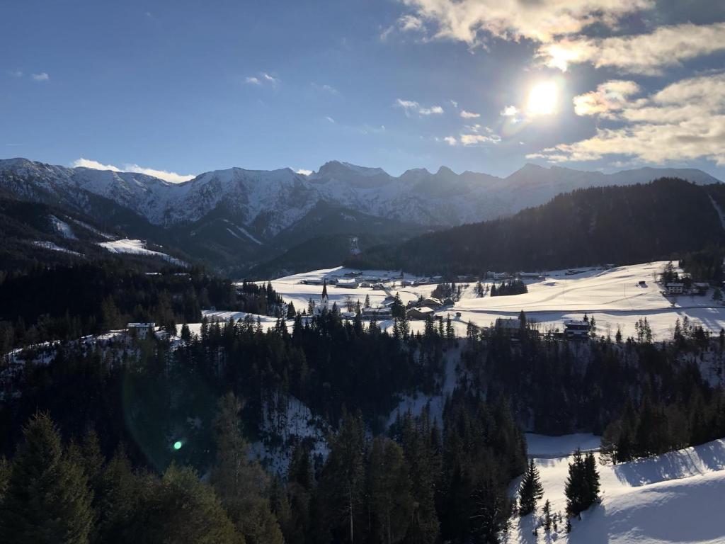 een uitzicht op een besneeuwde berg met de zon in de lucht bij Patagonien in Steinberg am Rofan