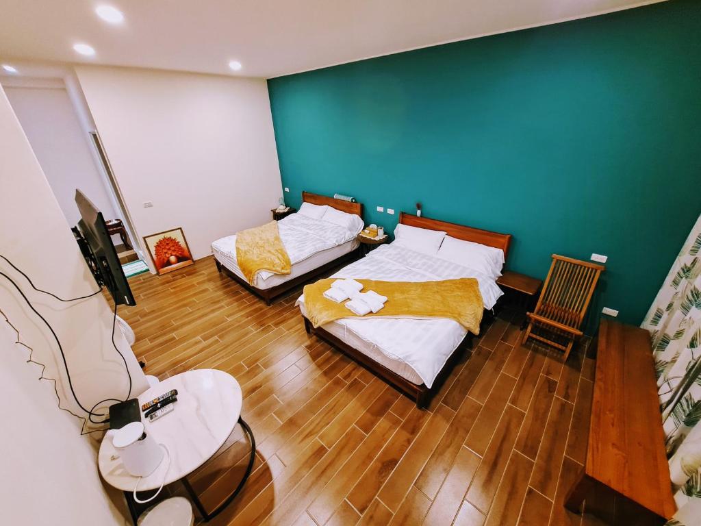 a bedroom with two beds and a green wall at Rainy Pleasure in Meishan