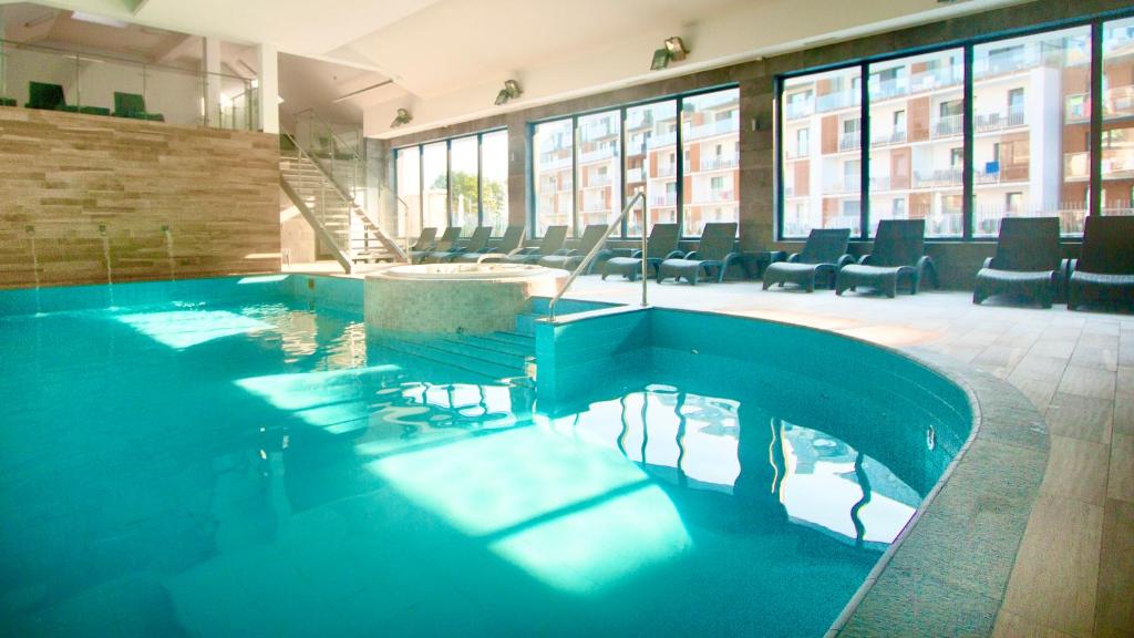 a swimming pool in a building with tables and chairs at OnHoliday Apartamenty ulica Poleska in Kołobrzeg