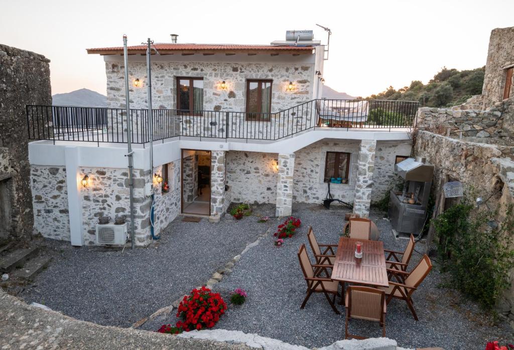 een stenen huis met een balkon en een tafel en stoelen bij Villa Sunshine Crete in Vathiakón