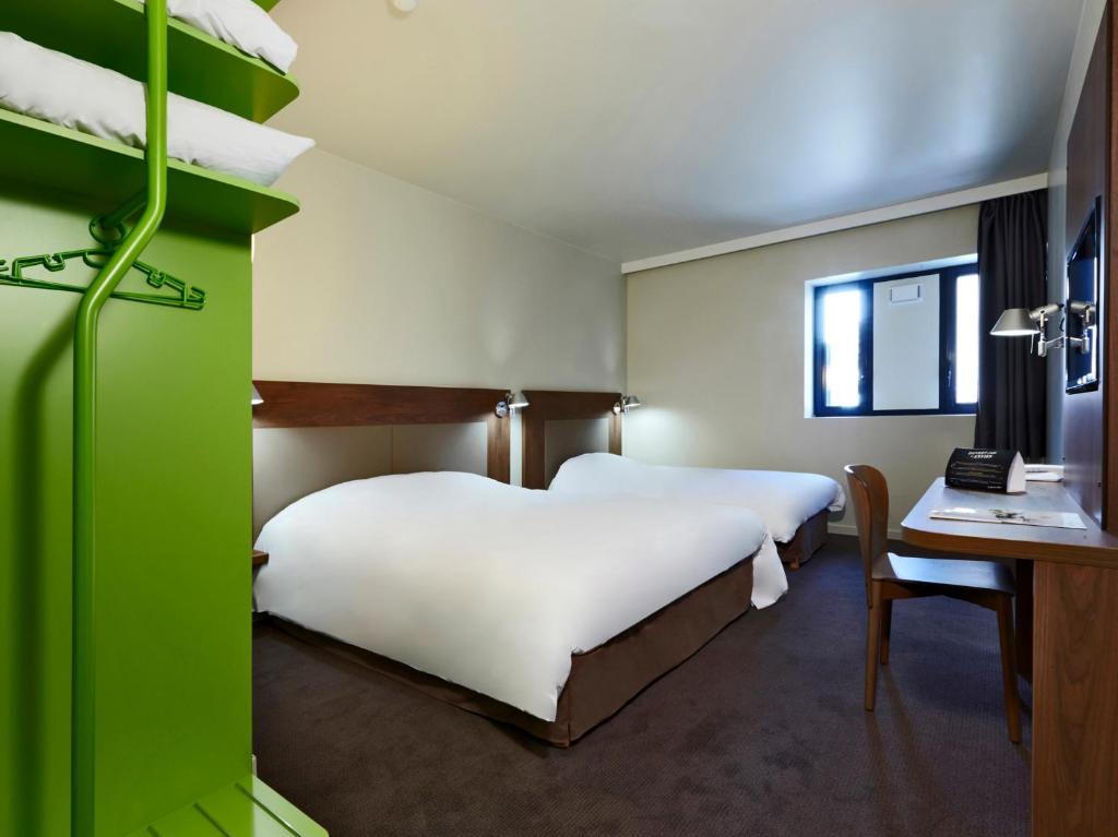 a bedroom with a large white bed and a desk at Campanile Nancy Centre - Gare in Nancy