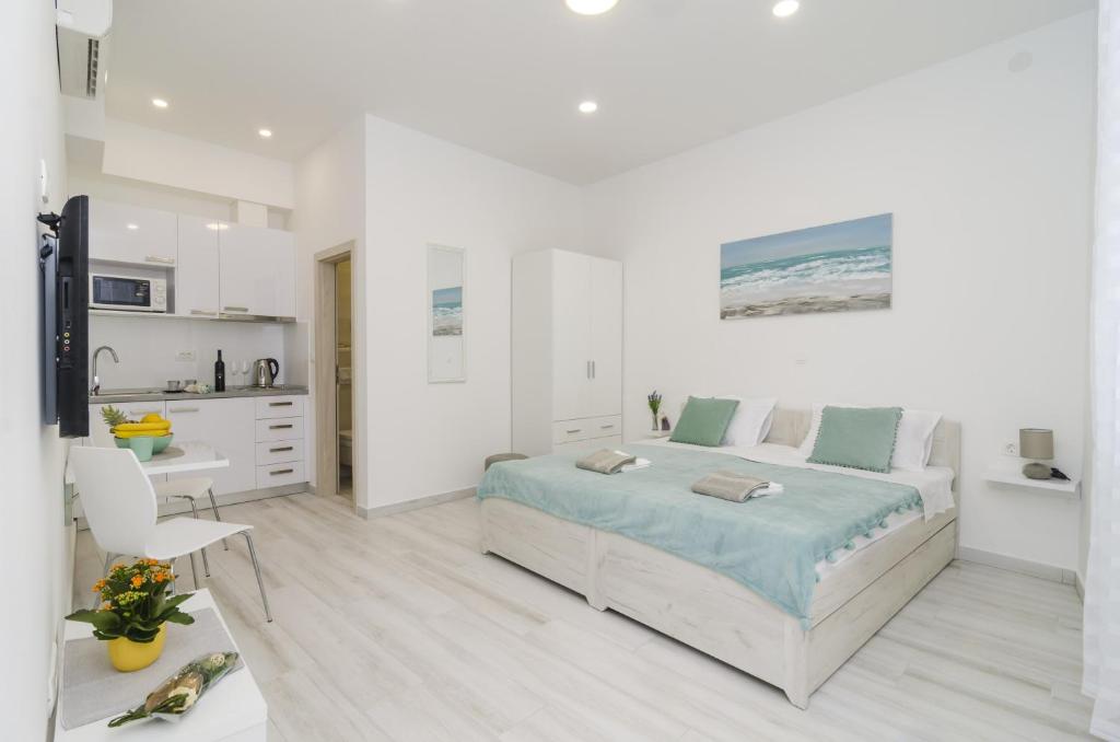 a white bedroom with a bed and a kitchen at Apartment Rafaello in Dubrovnik
