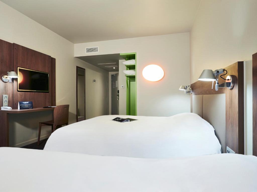 a hotel room with two beds and a television at Campanile Nancy Centre - Gare in Nancy