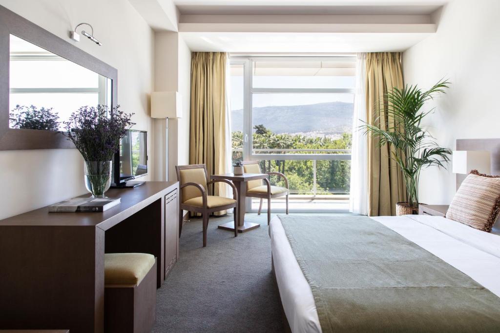 ein Hotelzimmer mit einem Bett und einem großen Fenster in der Unterkunft Amalia Hotel Athens in Athen