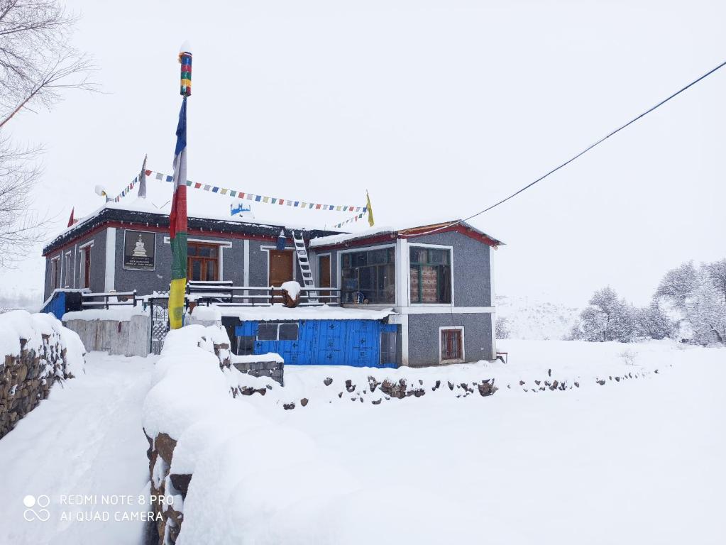 una casa cubierta de nieve con pájaros delante en Nizer khangchung Homestay, en Mani