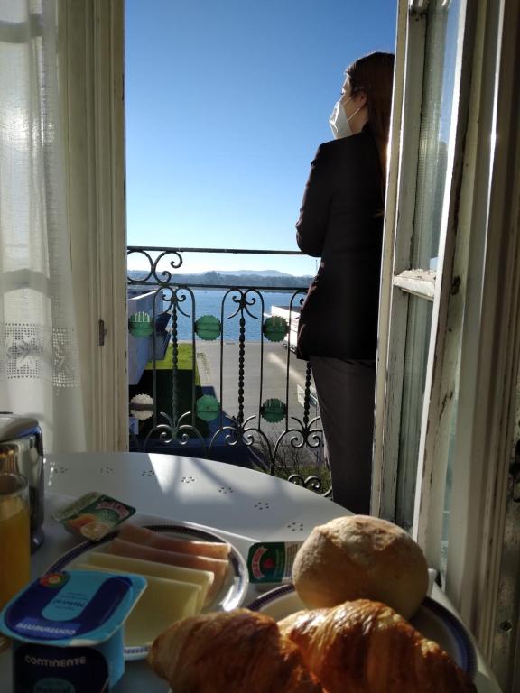 uma mulher de pé numa varanda com um prato de pão em Hotel Jardim Viana do Castelo em Viana do Castelo