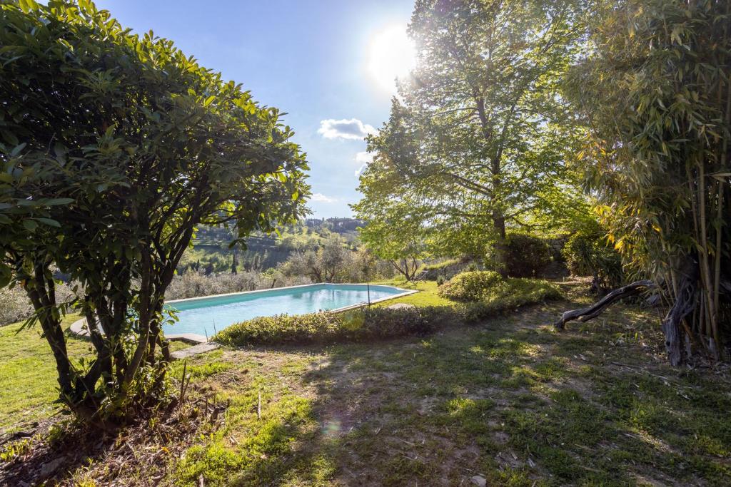 uma piscina num jardim com árvores em Isola del Pittore Fienile di Villa Storica em Grassina