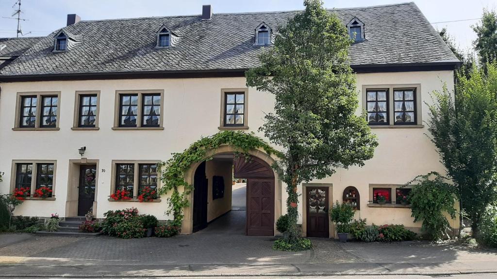 ein großes weißes Haus mit Torbogen in der Unterkunft Weingut Gorges-Reinhard in Wintrich