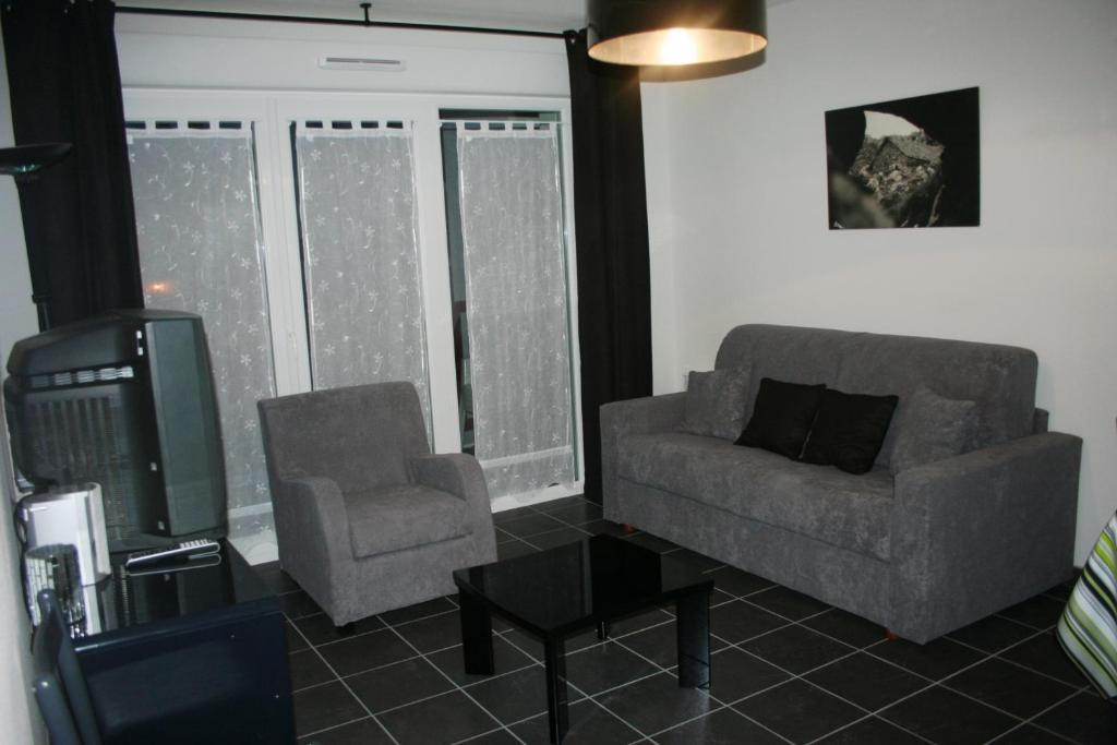 - un salon avec un canapé, une chaise et une télévision dans l'établissement Appartement Les Romanesques, à Cambo-les-Bains