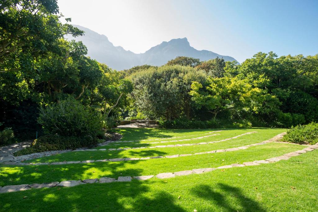 un campo de césped con árboles y montañas al fondo en Vineyard Hotel en Ciudad del Cabo