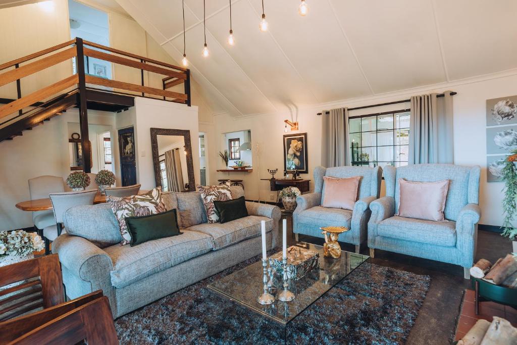 a living room with two couches and a table at Miracle Mountain Cottage in Howick