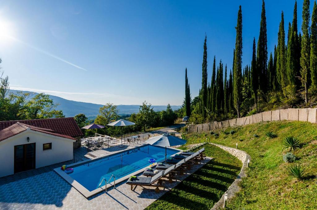 a swimming pool in a yard with chairs and a house at Villa Mlin in Gruda