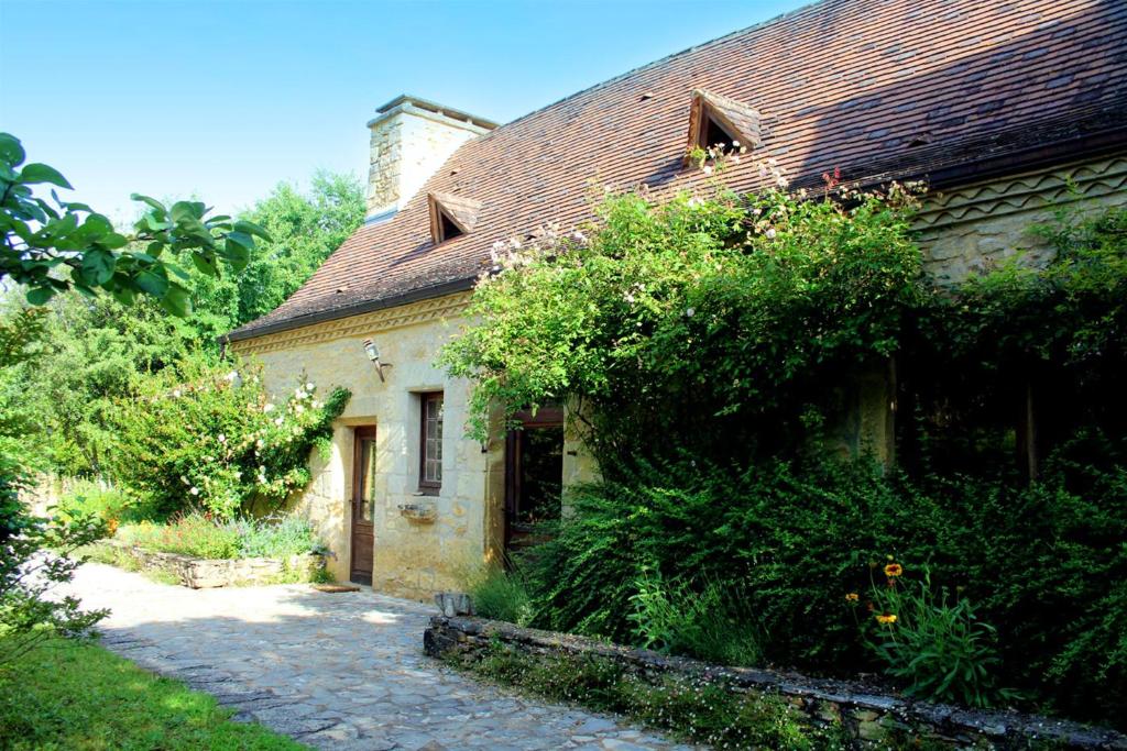 uma antiga casa de pedra com um passadiço de tijolos lá fora em Maison de 4 chambres avec piscine partagee et jardin amenage a Saint Cybranet em Saint-Cybranet