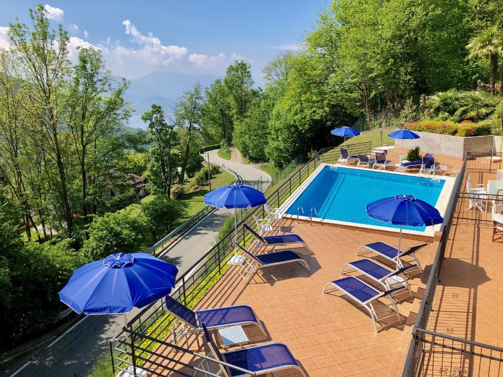 a swimming pool with blue umbrellas and lounge chairs at Residenza Ai Ronchi 3 4 7 8 in Maccagno Superiore