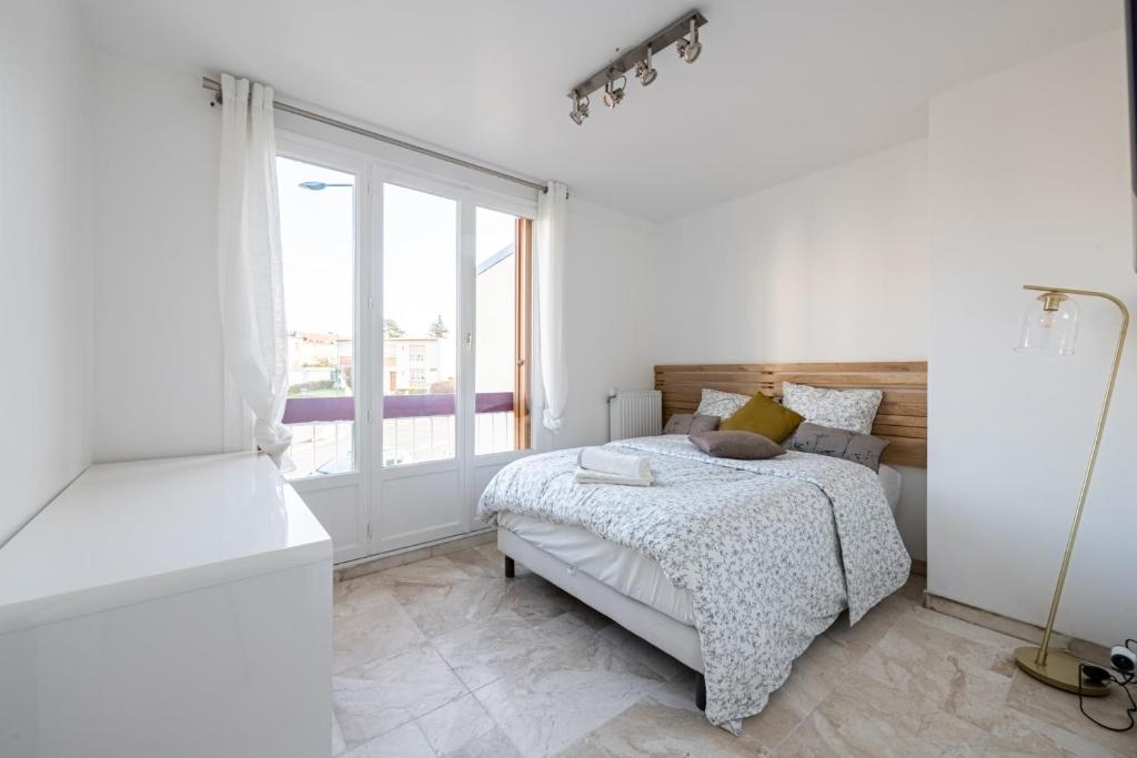 a white bedroom with a bed and a window at L&#39;Impressionniste in Pontoise