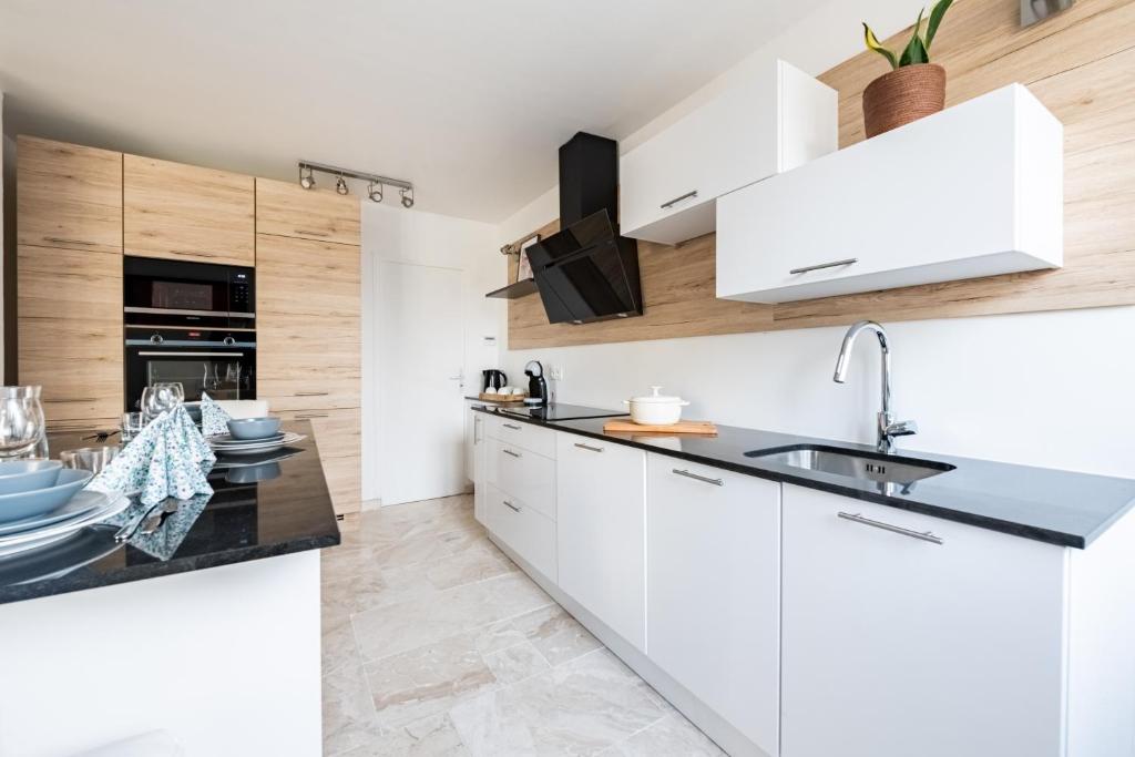 a kitchen with white cabinets and a sink at L&#39;Impressionniste in Pontoise