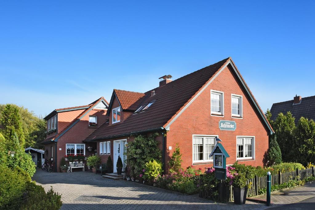 ein rotes Backsteinhaus mit schwarzem Dach in der Unterkunft Ferienwohnungen im Haus Kehrwieder in Neuharlingersiel