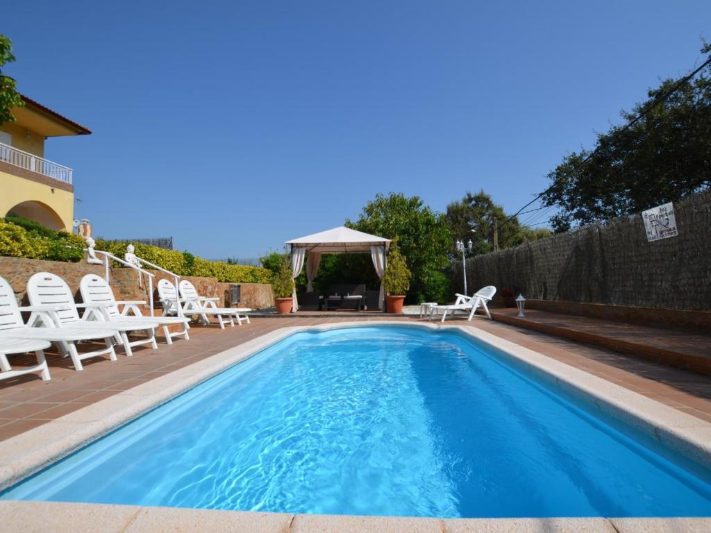 een zwembad met witte stoelen en een prieel bij Villa valen montbarbat costa brava in Maçanet de la Selva