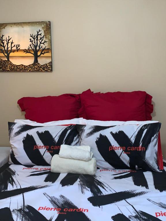 uma cama com lençóis pretos e brancos e almofadas vermelhas em Stonebass Lodge em Newlands